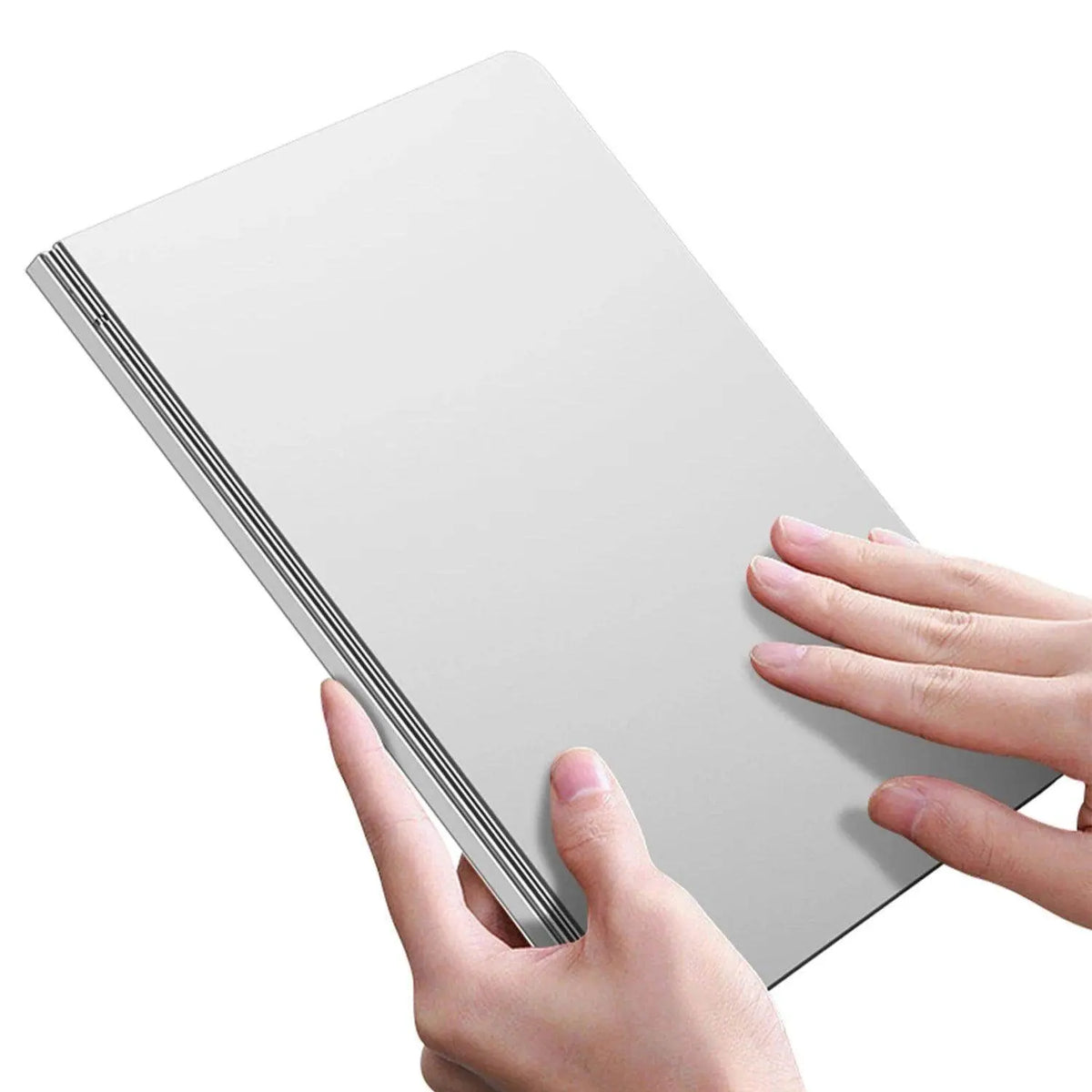 Person holding a slim, closed silver-gray notebook with black striped spine