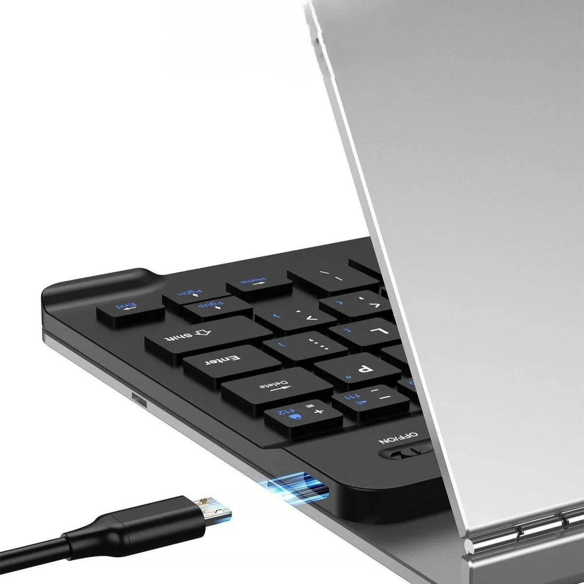 Close-up of black wireless numeric keypad with USB receiver and silver laptop edge